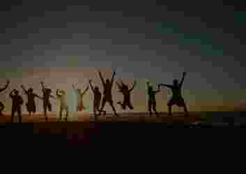 silhouette of people jumping at sunset
