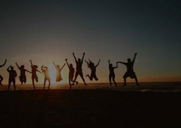 silhouette of people jumping at sunset