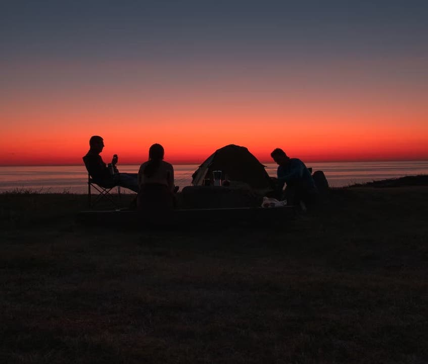 people camping on the beach at sunset