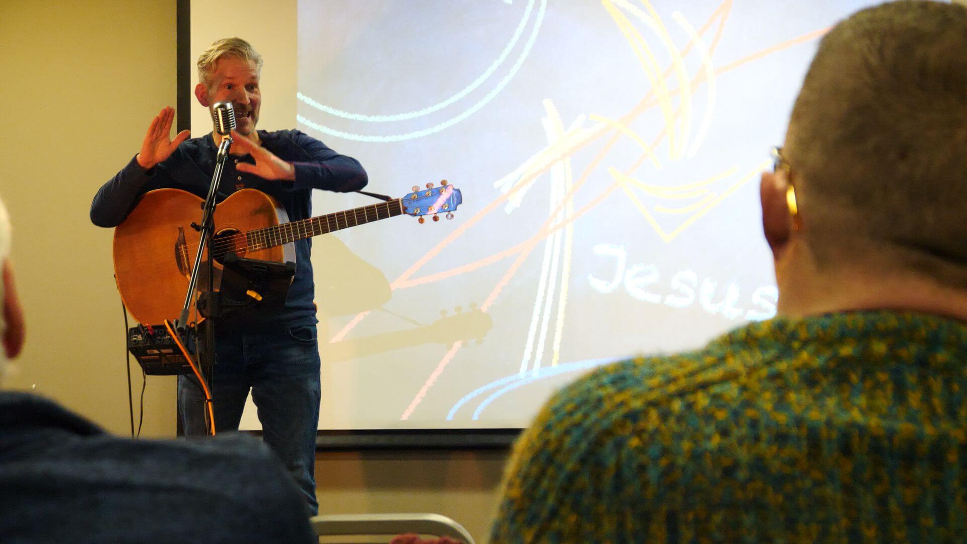 Man with a guitar presenting at a Christian Ceremony